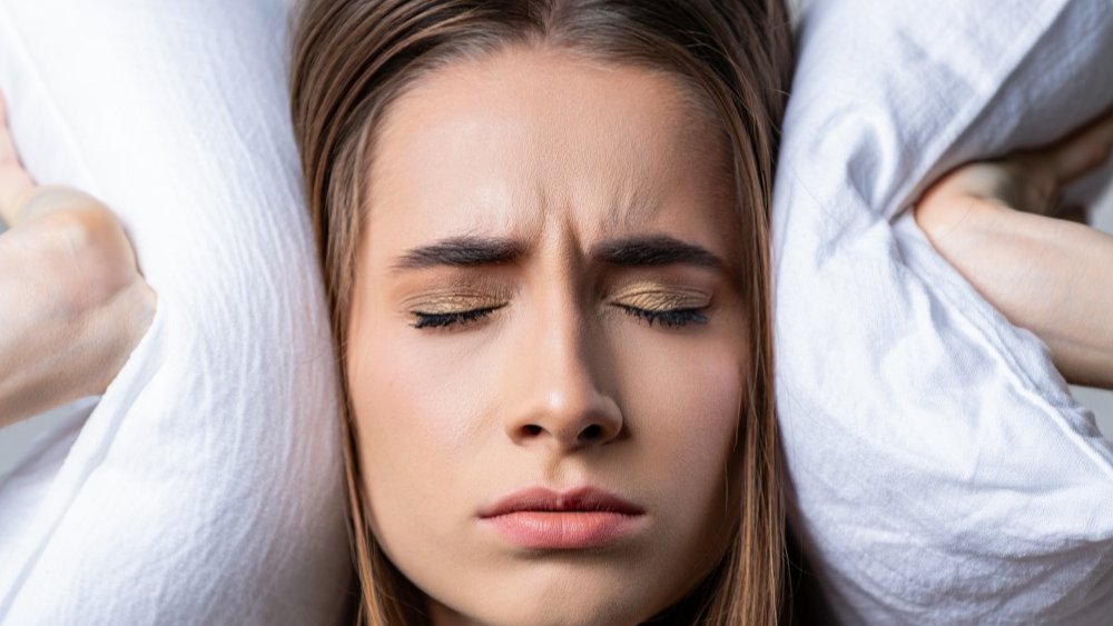девушка закрыла уши подушкой